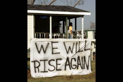 Survivors of Hurricane Katrina clean out their house after hanging a sign out front reading "We Will Rise Again" in Clermont Harbor, Mississippi September 7, 2005. Police threatened to force reluctant Hurricane Katrina survivors to leave a ruined and fetid New Orleans on Wednesday as a political storm grew over the botched response to the disaster that some say could cost $150 billion. REUTERS/Brian Snyder